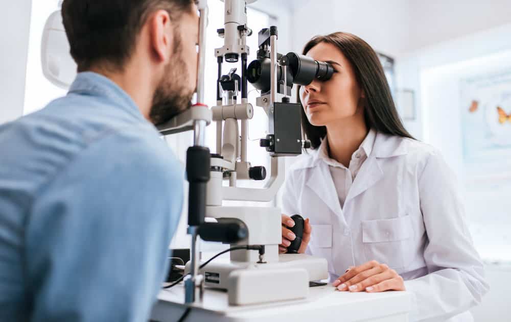 An eye doctor examines a patient using a slit-lamp machine.