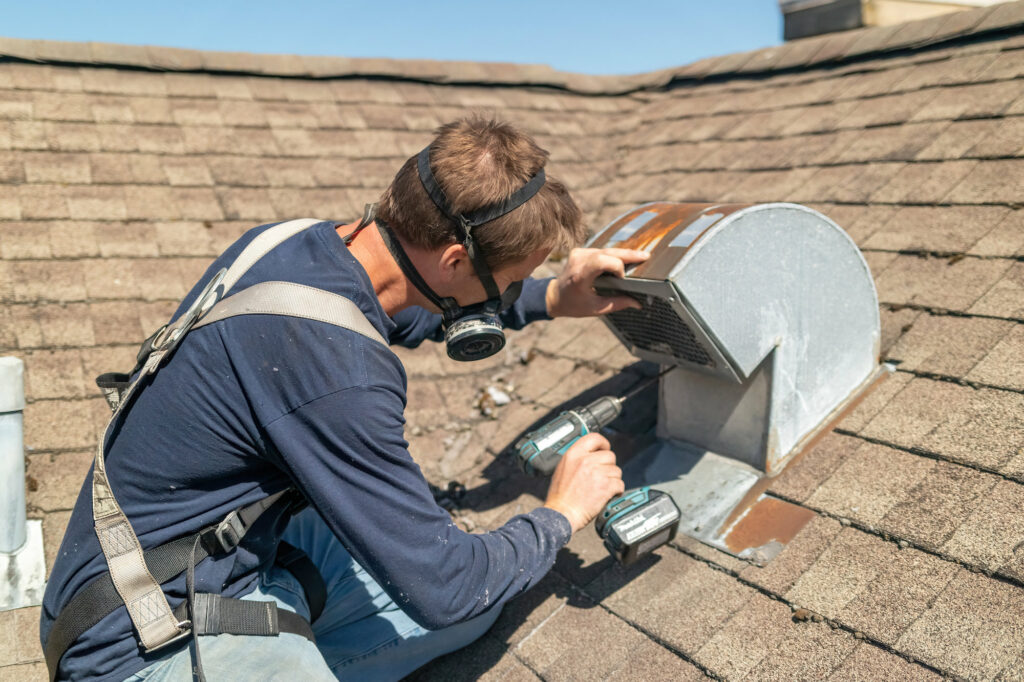 Roofer fixing a metal dryer vent