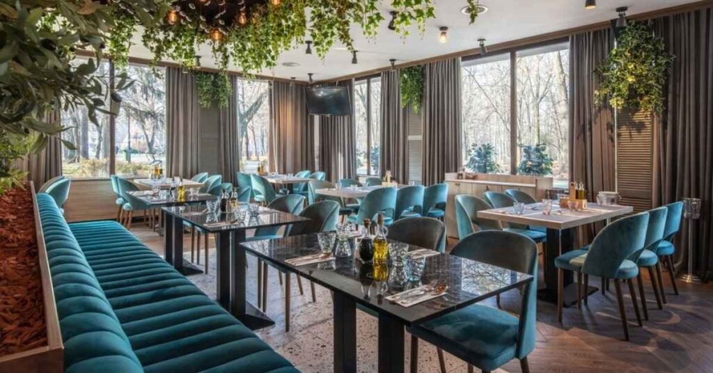Elegant indoor restaurant with teal seating and hanging greenery